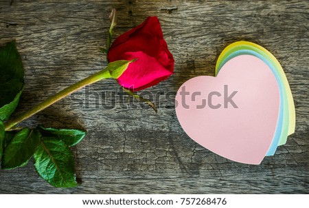 Note paper with red roses flowers on wooden background and Happy Valentine's Day.