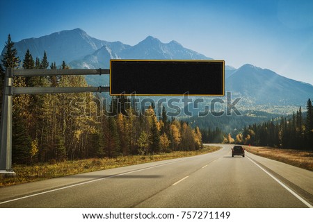 Autumn road across the Canadian Rocky Mountains. Traffic sign, board for arbitrary text. Concept of safety, restriction, information, message for drivers. Sunny day clear sky, road info, Alberta.