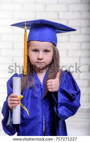 Portrait of cute schoolgirl with graduation hat in classroom