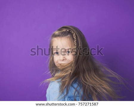 young 8 year old girl portrait in front of violet background in studio