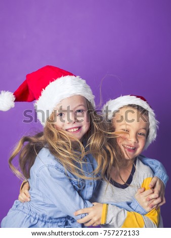 brother and sister with christmas decoration on head in front of violet background