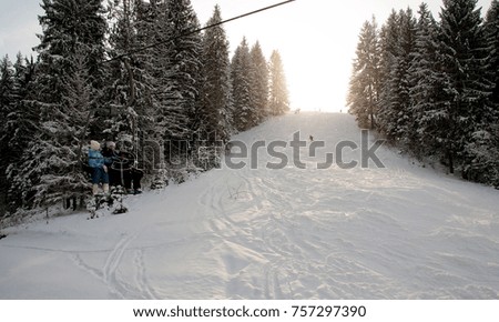 People rises on the lift in Carpathian mountains. On background of forest and ski slopes. Close up. Winter nature. Heavy snow falls. Side view. and looking down.