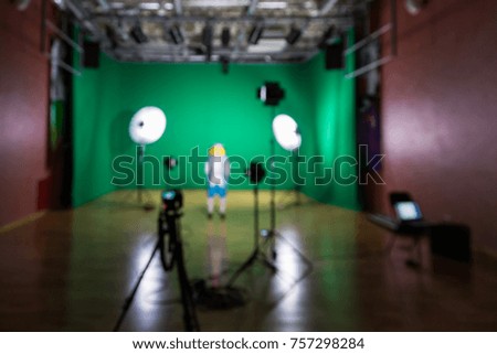 Blurred image. Shooting the movie on a green screen. The chroma key. Studio videography. Actress in theatrical costume. The camera and lighting equipment.