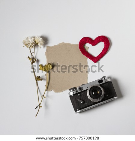 Heart, dry flower, retro camera and clean sheet of paper, on white background. Top view, flat lay.