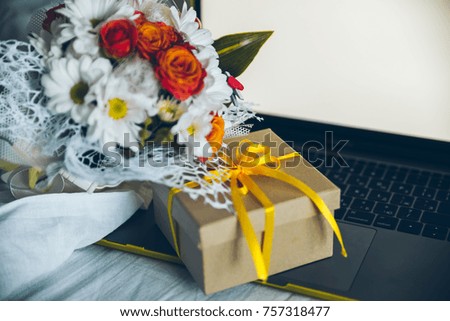 gift box with laptop with white screen and flowers on background