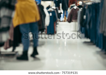Woman looking at price tag of clothes in shopping mall out of focus
