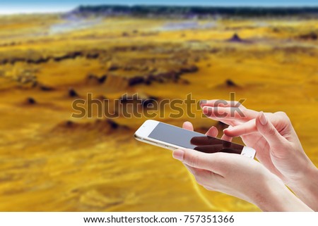 woman hand hold and touch screen smart phone or cell phone on blurred beautiful Mars background