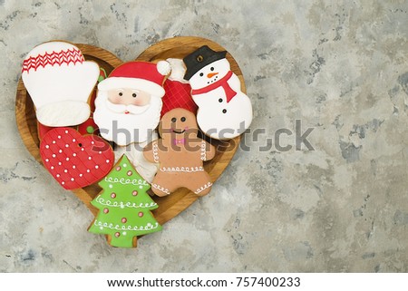 Christmas gingerbread cookies in wooden heart shaped plate on textured background top view, copy space