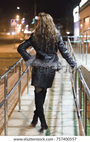 Beautiful girl at night in the city.
View of the girl behind in the background of the lights of the night city