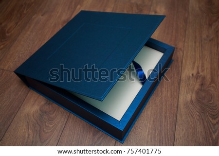 
stylish square dark blue cardboard box for a photo album close up on background with copy space for text.
Bright  box for wedding album.
leather photo book in open box
 for photobook