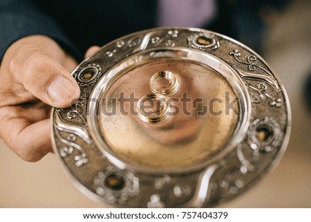 Man holds golden plate with wedding rings in church