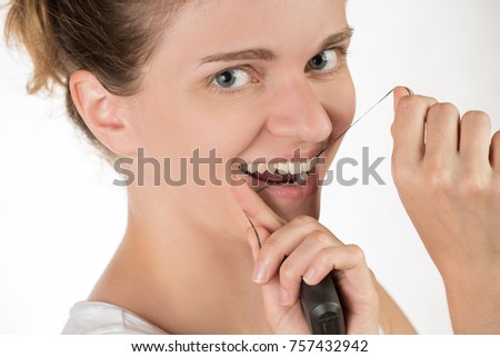 Hygiene of the oral cavity. Young girl cleans teeth with floss, smiling and showing okay sign on white background.