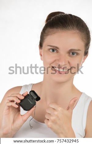 Hygiene of the oral cavity. Young girl cleans teeth with floss, smiling and showing okay sign on white background.