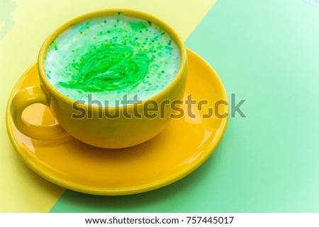 rainbow cappuccino in a bright yellow mug on bright yellow and green background.