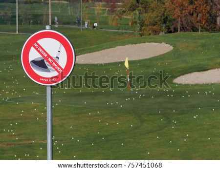 Golf club prohibition sign. No driver, no woods on the upper level. Meadow with many golf balls on background