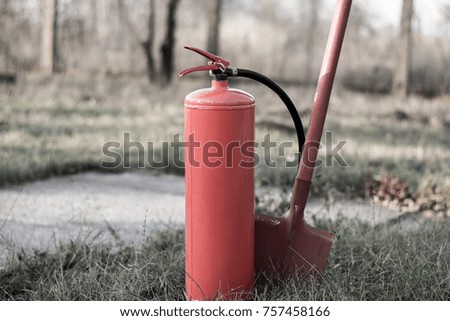 Fire extinguisher and shovel in an open area. blurred background