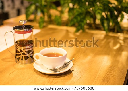 Cup of tea with cozy atmosphere in café or at home with green leaves and copy space