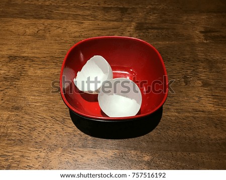 broken white egg in red bowl on wood table