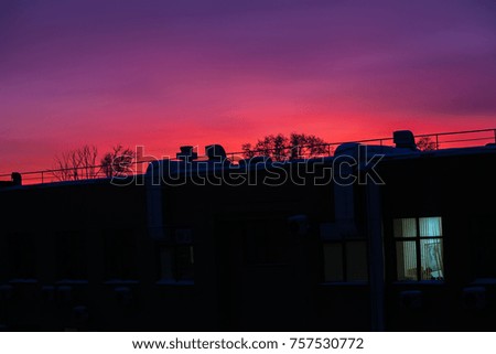 bright window in a dark house against the pink sunset