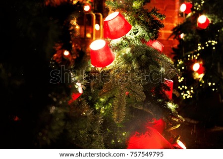 photo of Red lanterns on a branch of a Christmas tree on a red brick wall background