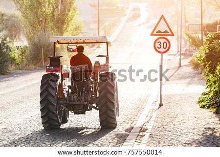 Tractor rides on the pavement road in the sunlight