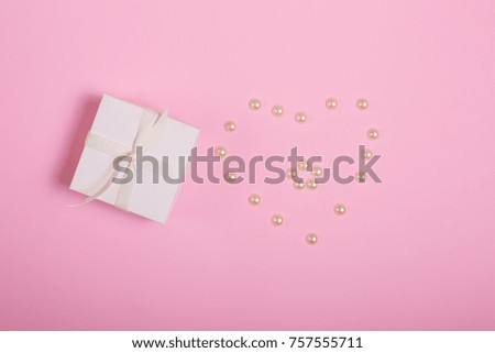Gift box with pearls on a pink background