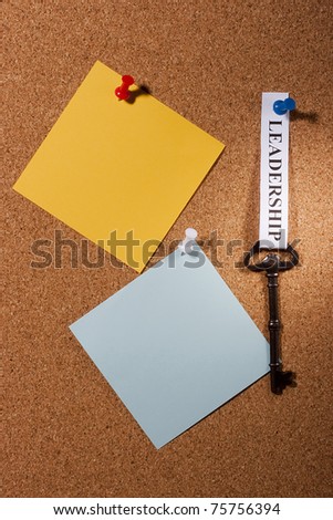Key with a leadership tag pinned on a brown board. Add your text to the background.