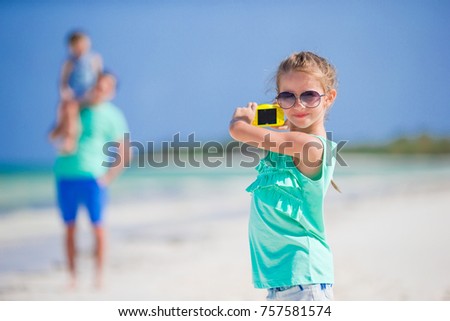 Little girl making photo on phone of her family at the beach