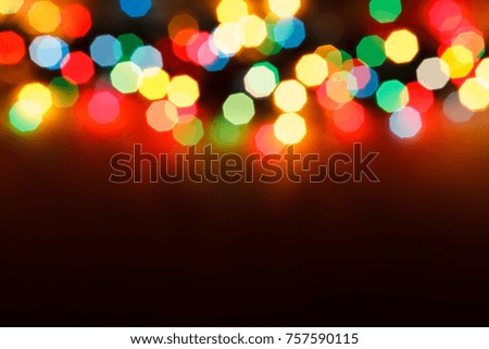 Glowing Christmas garland on the wooden background in the darkness with some free space for your text or sign. Christmas garland lying on the wood floor. Christmas decorations. New Year.