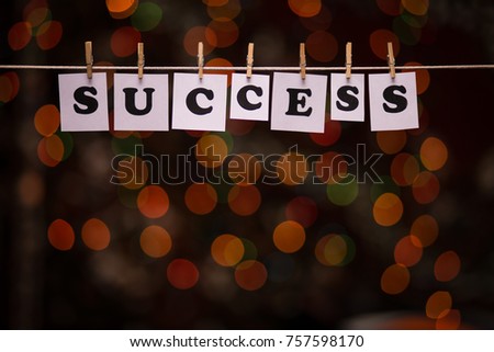Success text on papers with clothespins with garland bokeh on background. The word "Success". Success concept