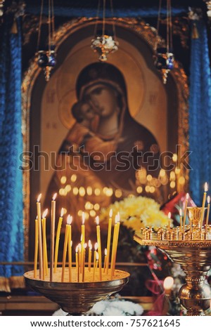 Image of a holy icon in the Orthodox Church. The candles burn nearby and are reflected on the glass