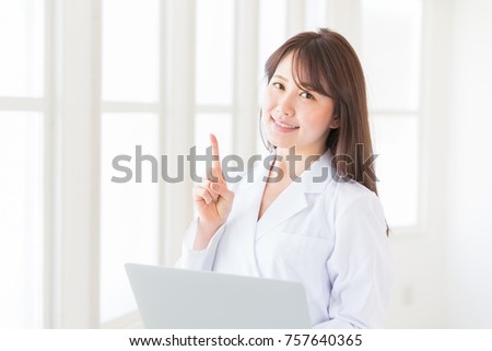 Young attractive asian woman in a white coat, laptop
