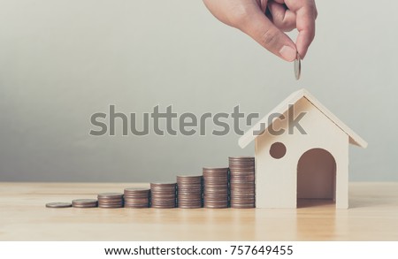 Property investment and house mortgage financial concept, Hand putting money coin stack with wooden house Royalty-Free Stock Photo #757649455