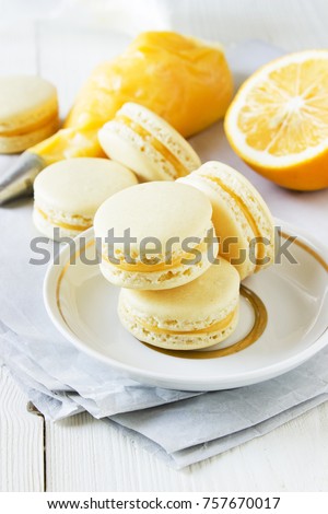 Lemon Macarons with lemon curd, lemon, piping bag on a white wooden table