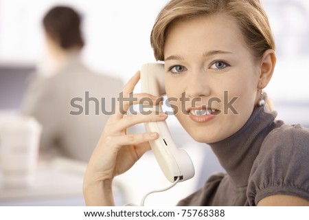 Closeup portrait of young woman talking on phone. Looking at camera, smiling.