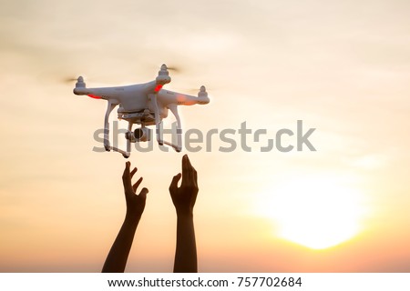 The UAV drone and photographer man hands. drone copter flying with digital camera. UAV Drone with digital camera. Flying camera take a photo and video. The drone with camera takes pictures of the sky. Royalty-Free Stock Photo #757702684