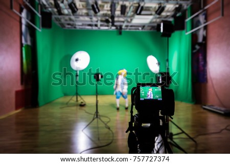 Shooting the movie on a green screen. The chroma key. Studio videography. Actress in theatrical costume. The camera and lighting equipment.
