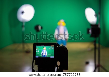 Shooting the movie on a green screen. The chroma key. Studio videography. Actress in theatrical costume. The camera and lighting equipment.