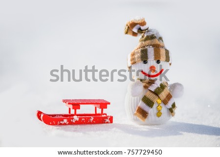 Toy snowman and red sleigh on snow. Winter card