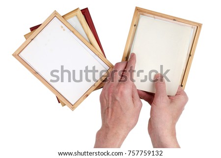 Old man grandfather inserts photos into wooden photo frames. Nostalgia by youth  concept.Isolated on white top view studio shot