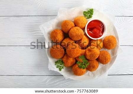 delicious potato croquettes - mashed potatoes balls with grated mozzarella cheese seasoned with spices; breaded and deep fried in olive oil, served with ketchup on white plate, view from above Royalty-Free Stock Photo #757763089