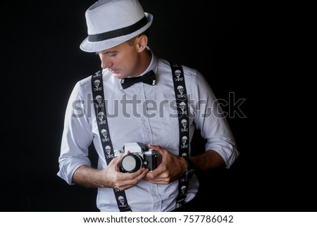 Young stylish photographer with retro camera over black background