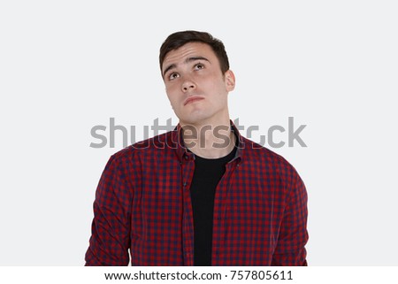 Isolated picture of thoughtful young European male with smooth face looking up with confused pensive expression, feeling indecisive and doubtful while can't make difficult decision or choice