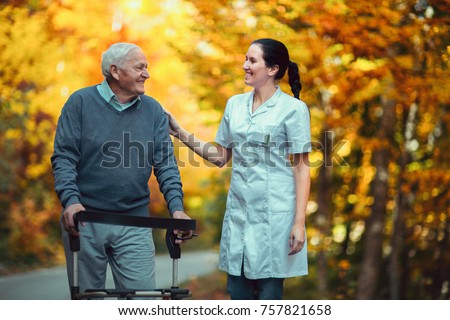 Nurse helping elderly senior man. Senior man using a walker with caregiver outdoor