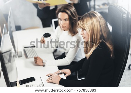 Two beautiful business woman making conversation at modern lightfil office.Handsome girls at working process.Horizontal,blurred background