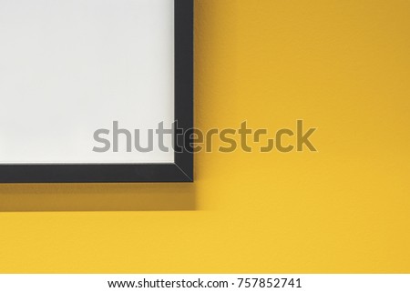 Simple black picture frame corner on a bright yellow blank wall.