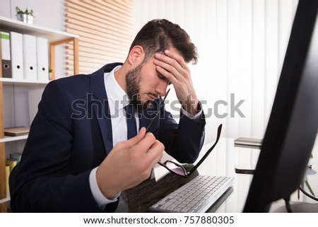 Young Businessman Suffering From Headache Sitting In Front Of Computer