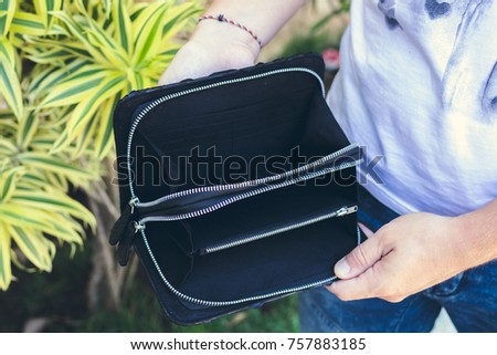 Man holding handmade purse made from exotic leather snakeskin python, outdoors, green tropical background.