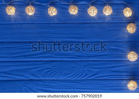 christmas garland lights on blue wooden background with copy space for your text. Top view