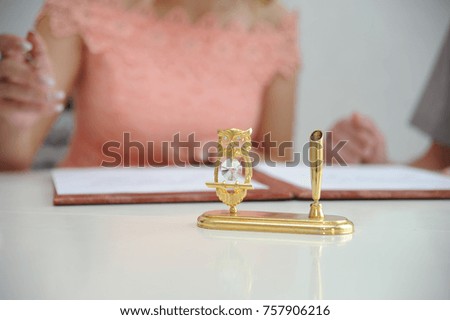 Stand for a written device in the form of an owl, in the background the bride signs documents on marriage